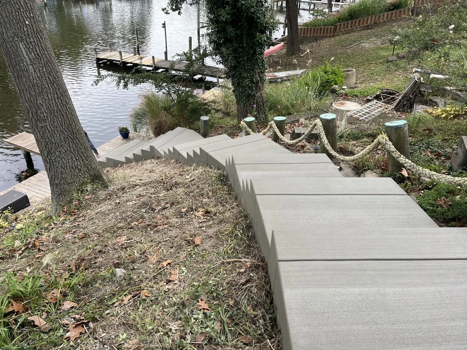 Freshly poured concrete steps descending a grassy slope toward a lake with wooden docks