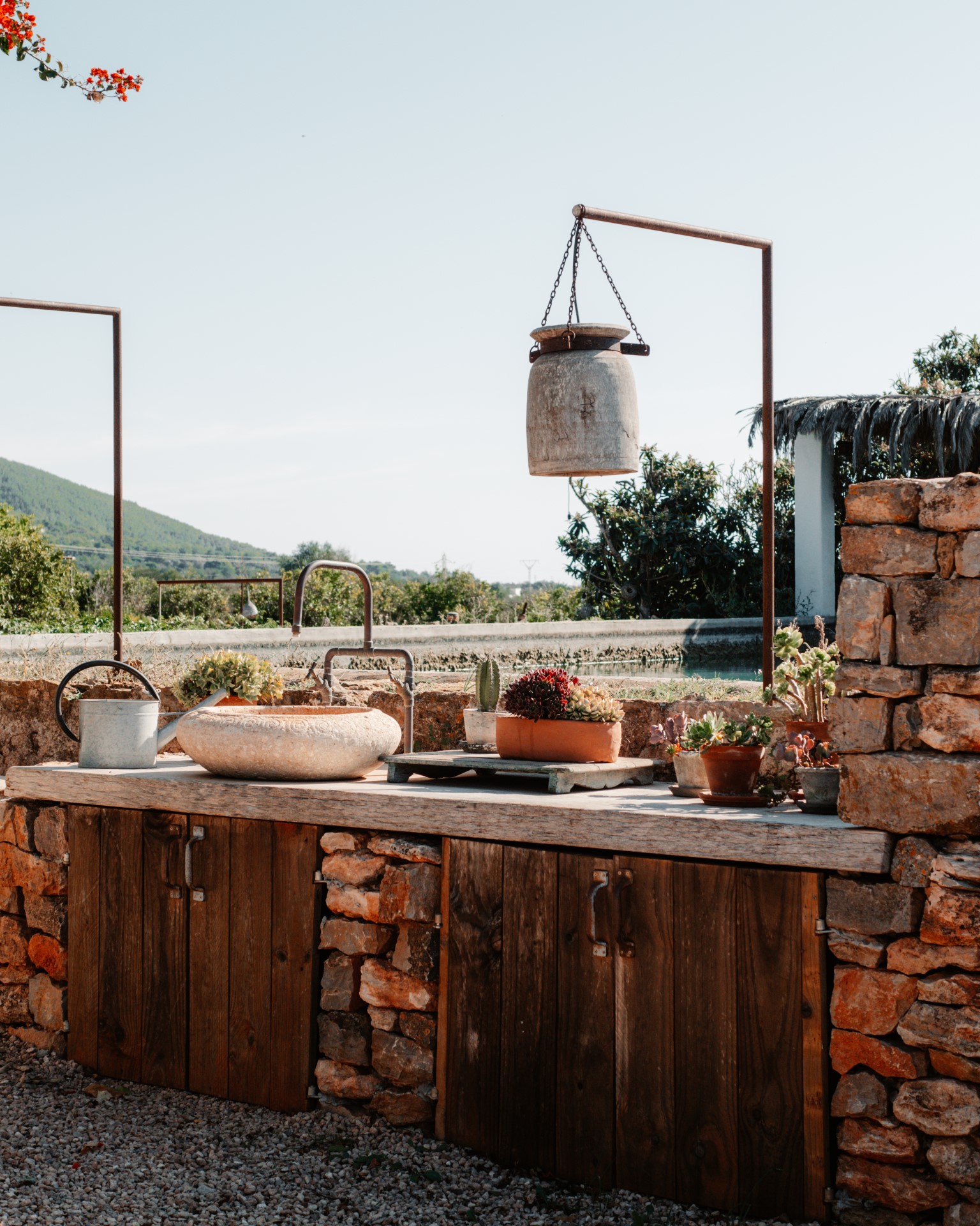 A rural outdoor kitchen with a cooking pot and cabinets on a concrete patio.