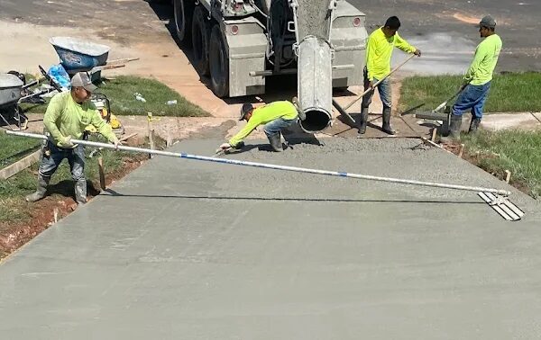 Construction worker smoothing wet cement for a driveway installation